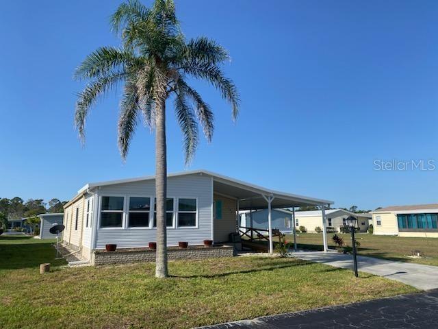 A light-colored manufactured home with a palm tree in the front yard — 707 DEL LUNA DRIVE, NORTH PORT, FL