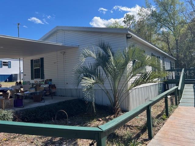 A white mobile home features a carport, a palm tree, and a wooden wheelchair ramp — 15926 NE 13TH STREET, WILLISTON, FL
