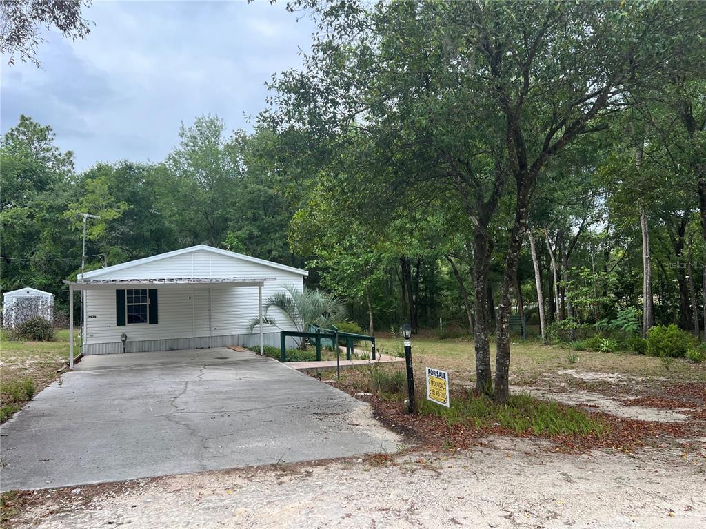 A white mobile home with a carport and a for sale sign in the yard — 15926 NE 13TH STREET, WILLISTON, FL