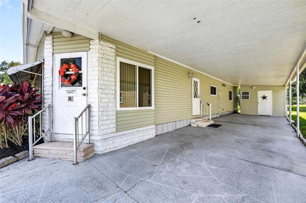 A light green mobile home exterior features a white front door, carport, and concrete driveway — 12501 ULMERTON ROAD UNIT 5, LARGO, FL