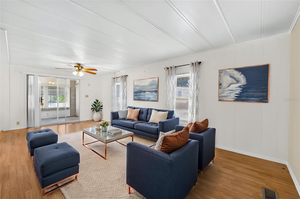 A living room features blue furniture, a glass coffee table, and white walls with artwork — 12501 ULMERTON ROAD UNIT 5, LARGO, FL