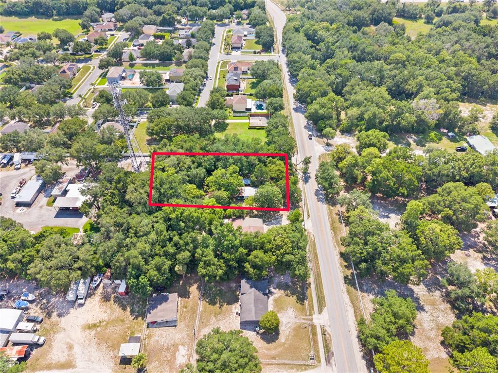 An aerial view shows a wooded lot outlined in red next to a paved road — 140 W PONKAN ROAD, APOPKA, FL