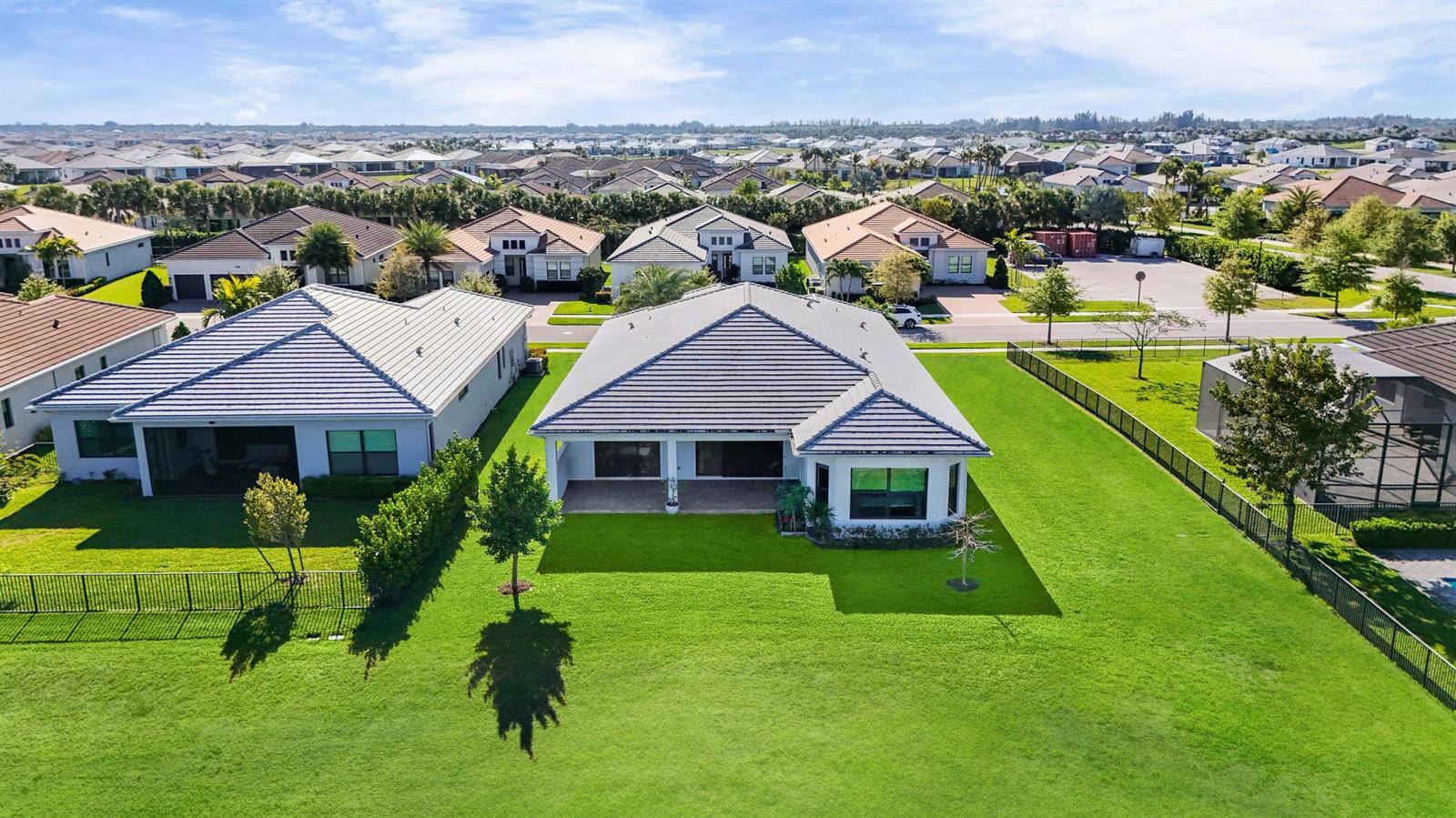 An aerial view shows the back of two suburban houses with tiled roofs and large lawns — 5353 Siesta Key Lane, Westlake FL 33470, WESTLAKE, FL