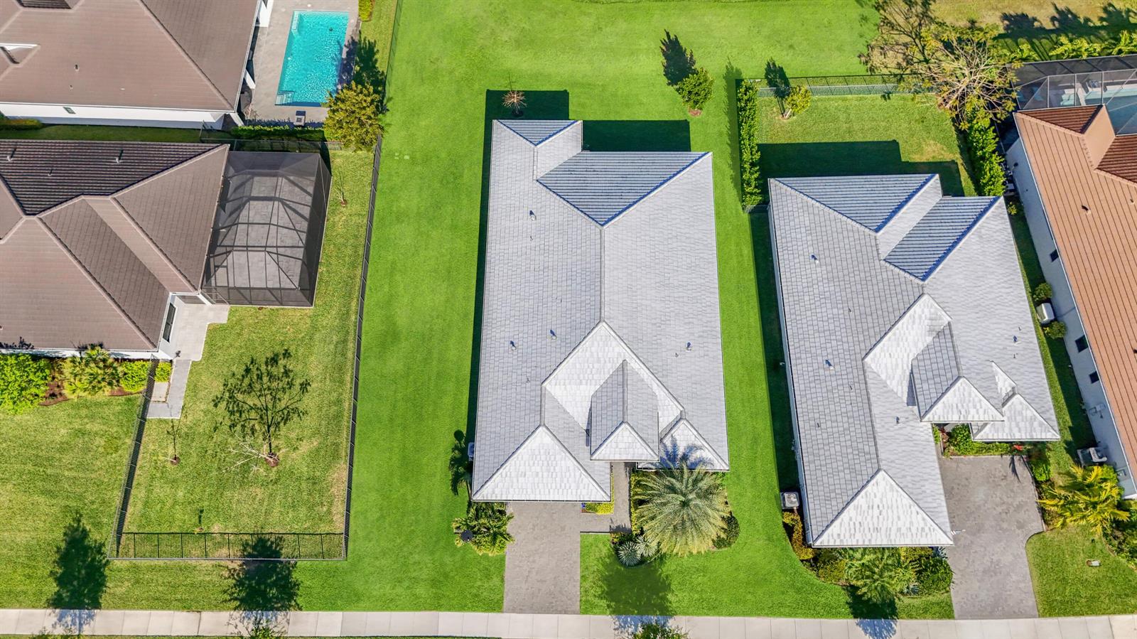 An aerial view shows three suburban houses with gray tile roofs and surrounding green lawns — 5353 Siesta Key Lane, Westlake FL 33470, WESTLAKE, FL