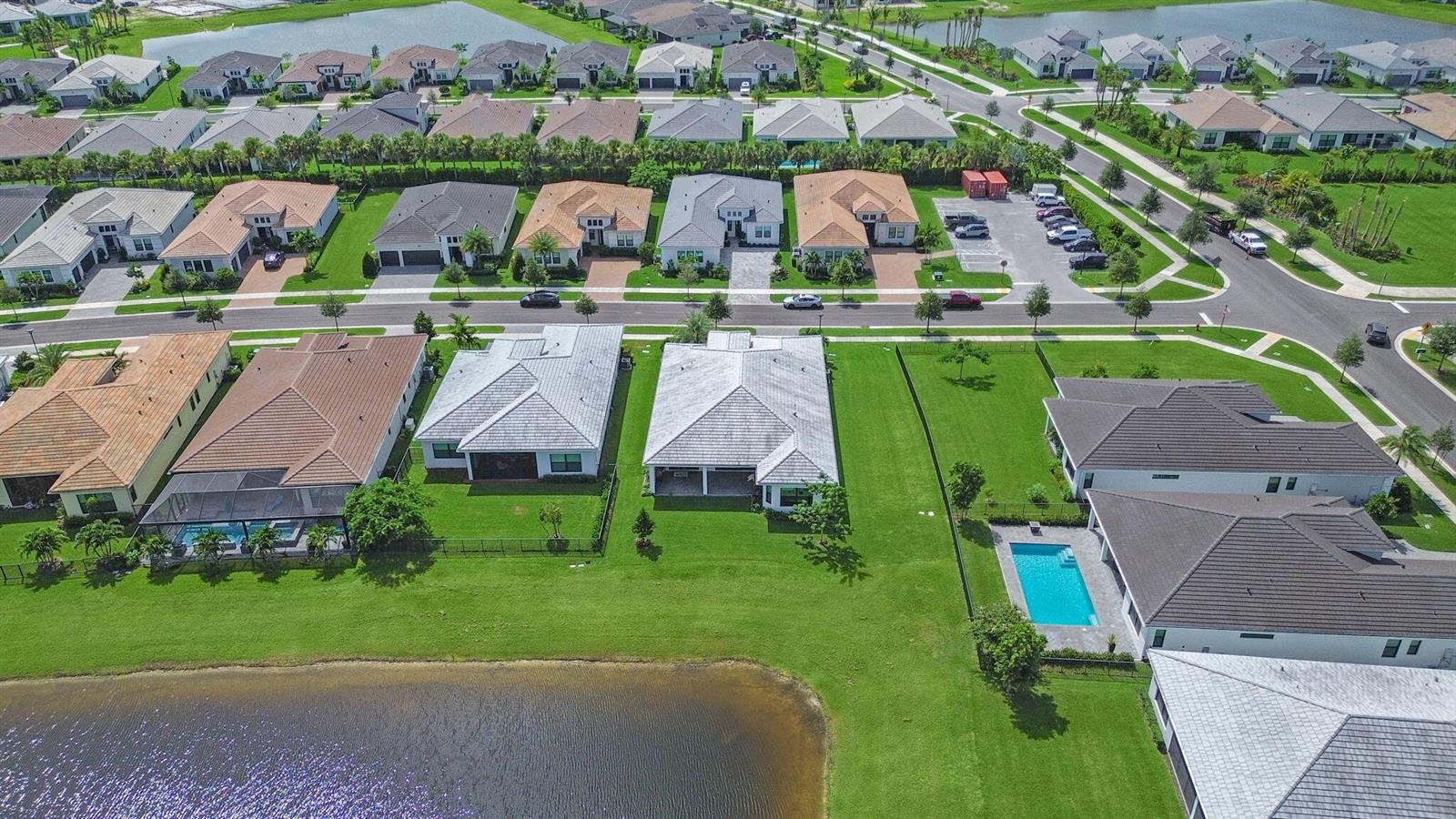 An aerial view shows a suburban neighborhood with single-family homes, manicured lawns, and a pond — 5353 Siesta Key Lane, Westlake FL 33470, WESTLAKE, FL