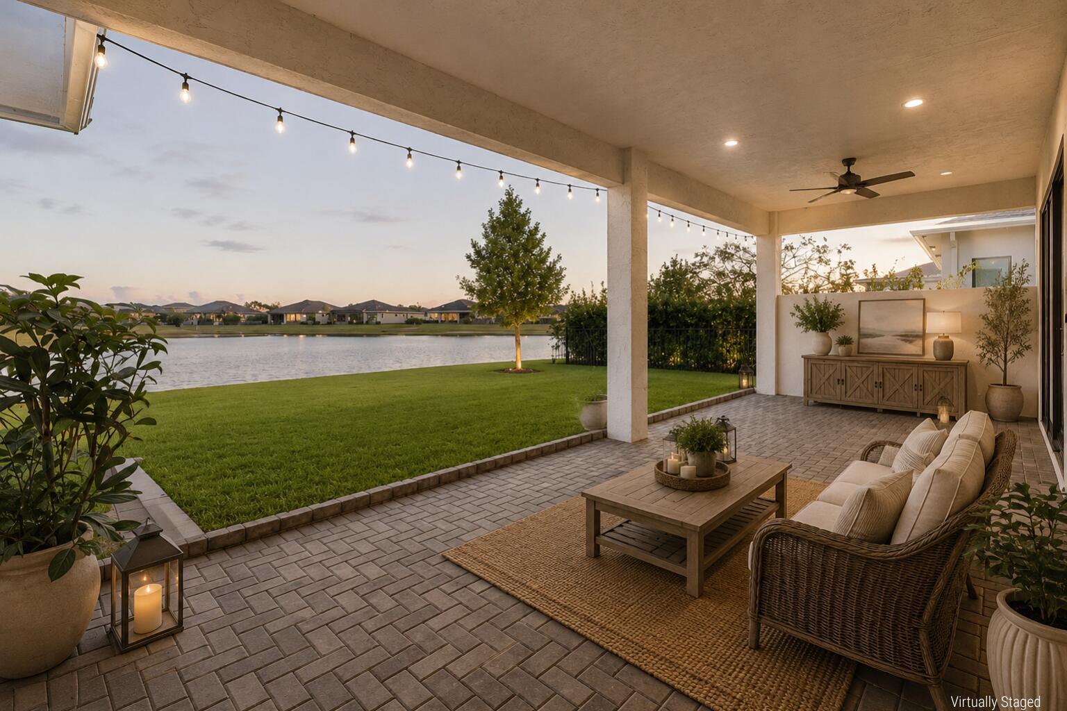 A covered patio with brick pavers overlooks a grassy lawn and a lake at sunset — 5353 Siesta Key Lane, Westlake FL 33470, WESTLAKE, FL