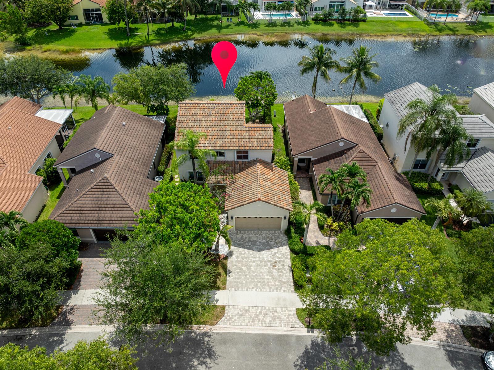 An aerial view shows a residential house with a tiled roof situated along a lake — 229 E Bayridge Drive, Weston FL 33326, WESTON, FL