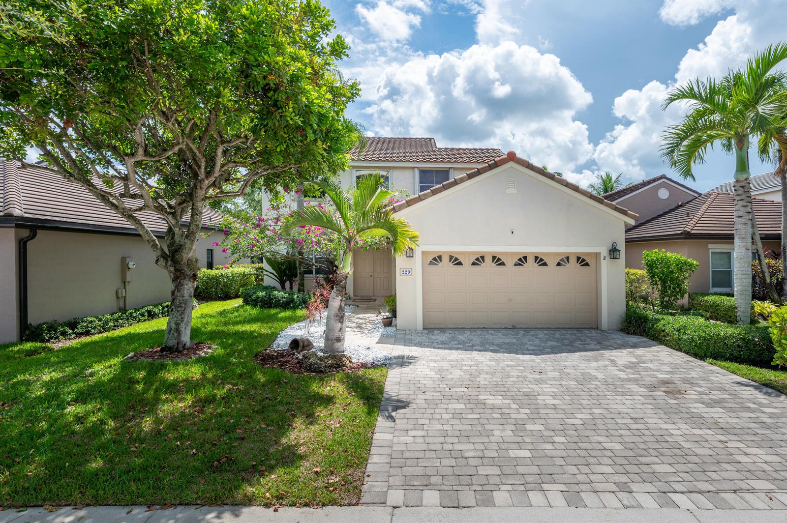 A two-story house with a beige garage, a paved driveway, and a large front tree — 229 E Bayridge Drive, Weston FL 33326, WESTON, FL
