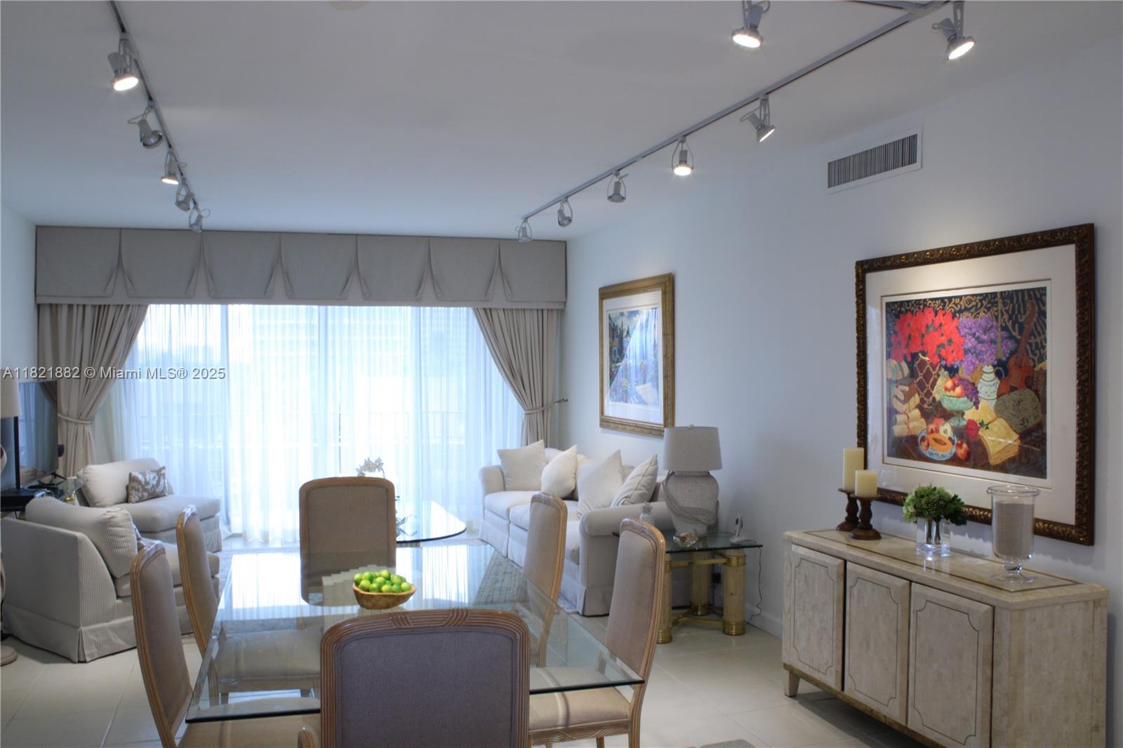 A dining area and living room feature a glass table, track lighting, and neutral furniture — 201 Crandon Blvd # 439, Key Biscayne FL 33149, KEY BISCAYNE, FL