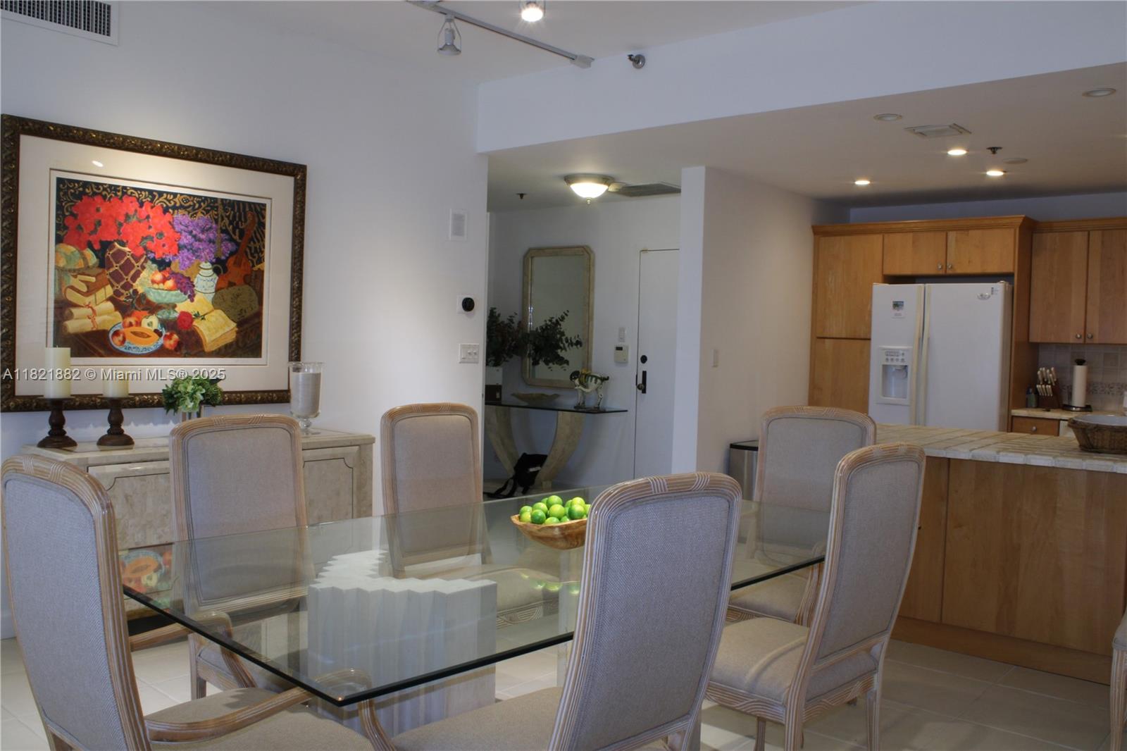 A dining area with a glass table and chairs sits adjacent to a wooden kitchen — 201 Crandon Blvd # 439, Key Biscayne FL 33149, KEY BISCAYNE, FL