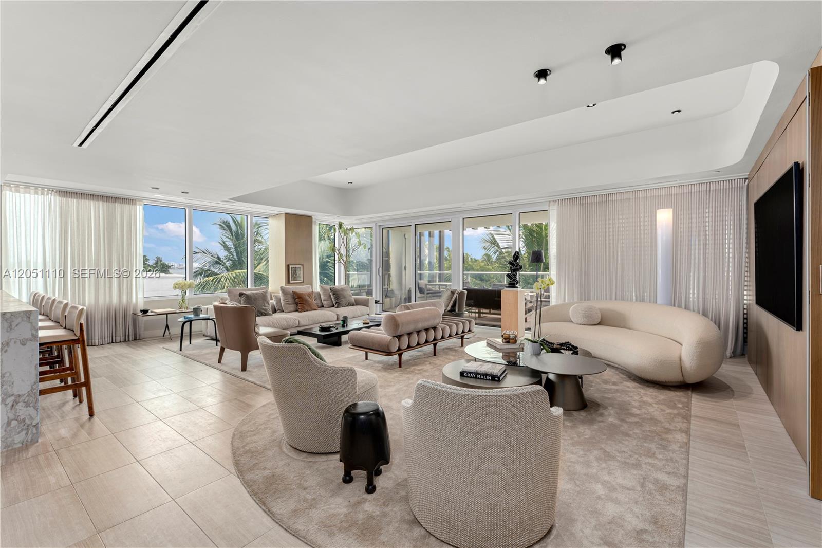 A spacious, modern living room features neutral furniture, large windows, and light-colored tile flooring — 4701 N Meridian Ave # 421, Miami Beach FL 33140, MIAMI BEACH, FL