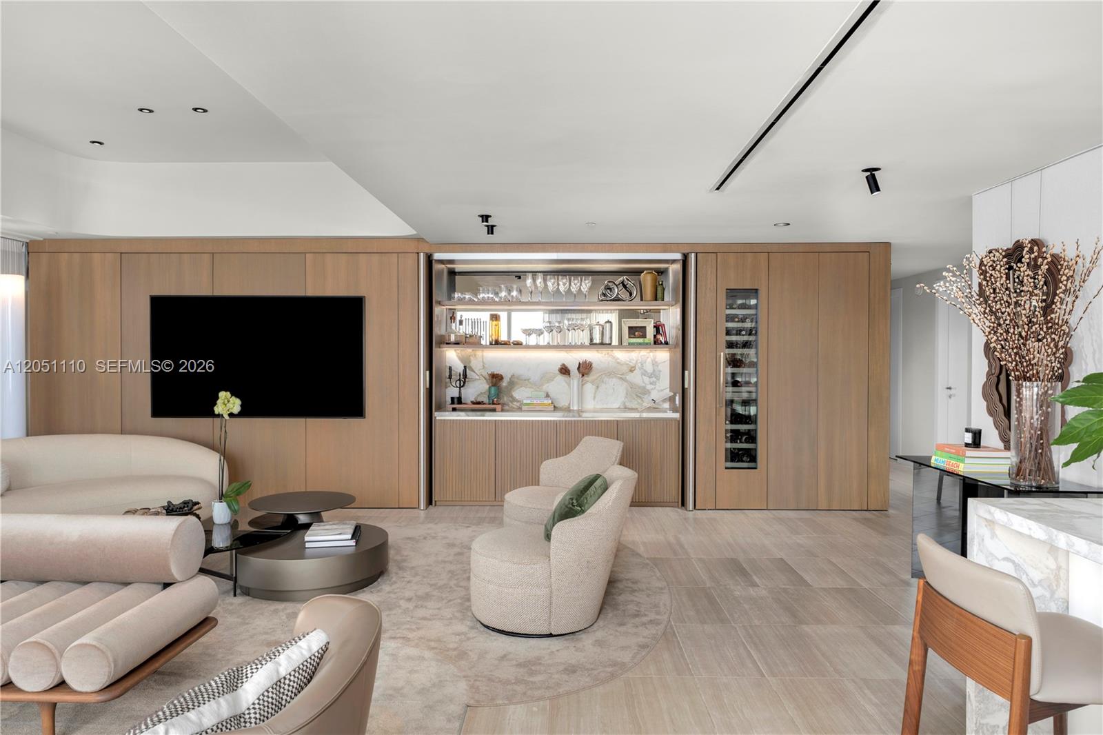 A modern living room features wood-paneled walls, a built-in bar, and neutral-toned furniture — 4701 N Meridian Ave # 421, Miami Beach FL 33140, MIAMI BEACH, FL
