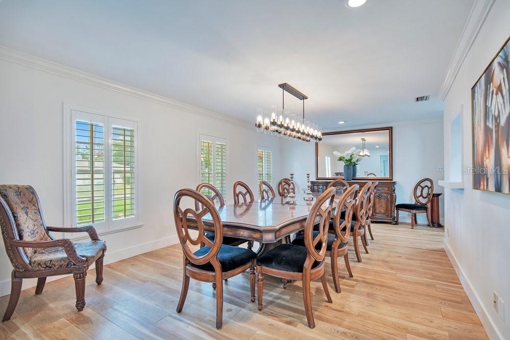 A dining room features a long wooden table, eight chairs, a chandelier, and light wood flooring — 614 BROOKWOOD LANE, MAITLAND, FL