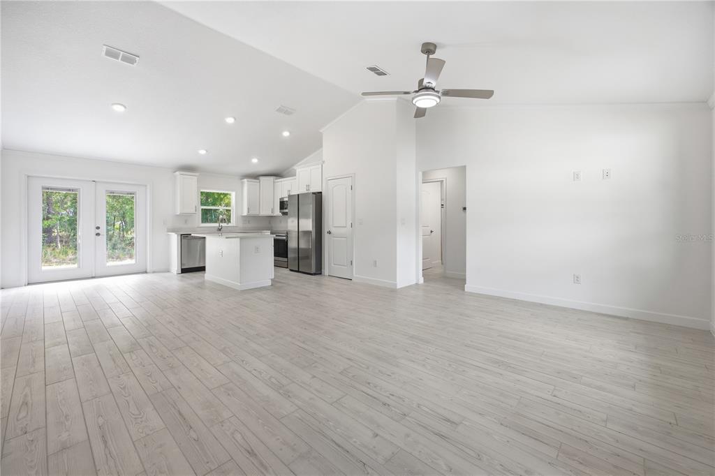 An open-concept kitchen and living area features white cabinetry, stainless steel appliances, and light flooring — 15649 SW 40TH STREET, OCALA, FL