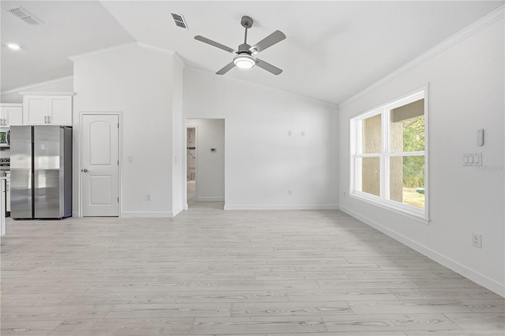 A bright, open-concept living area features white walls, light wood-look flooring, and a ceiling fan — 15649 SW 40TH STREET, OCALA, FL