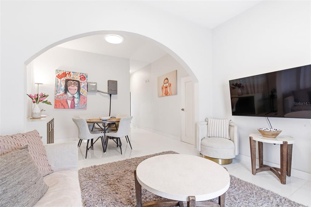A living room and dining area with white tile floors and an arched entryway — 56 CALLE F KRUG CONDADO UNIT 6, SAN JUAN, PR