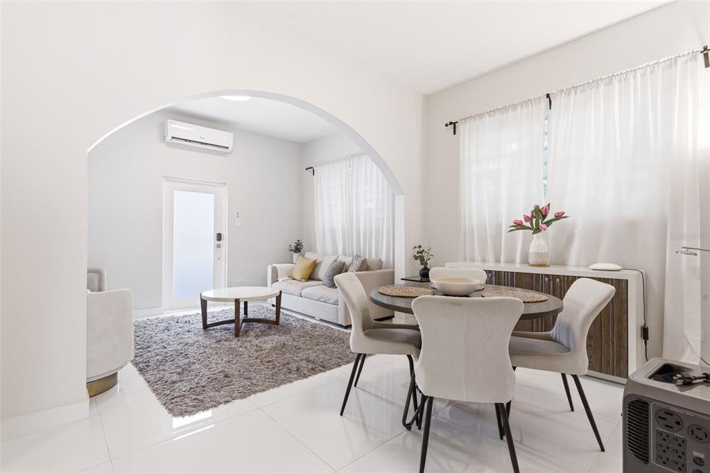 A bright living and dining area features white tile floors, an arched entryway, and furniture — 56 CALLE F KRUG CONDADO UNIT 6, SAN JUAN, PR