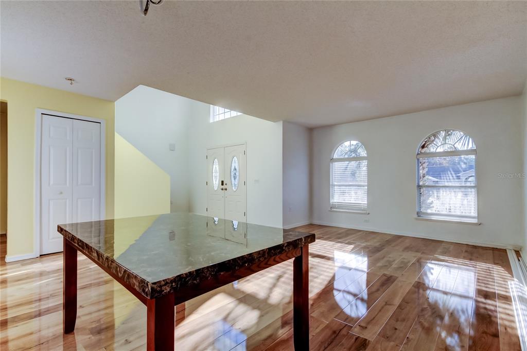 A dining area with a marble-topped table, hardwood floors, and arched windows near the entryway — 11309 OUTRIGGER AVENUE, SPRING HILL, FL