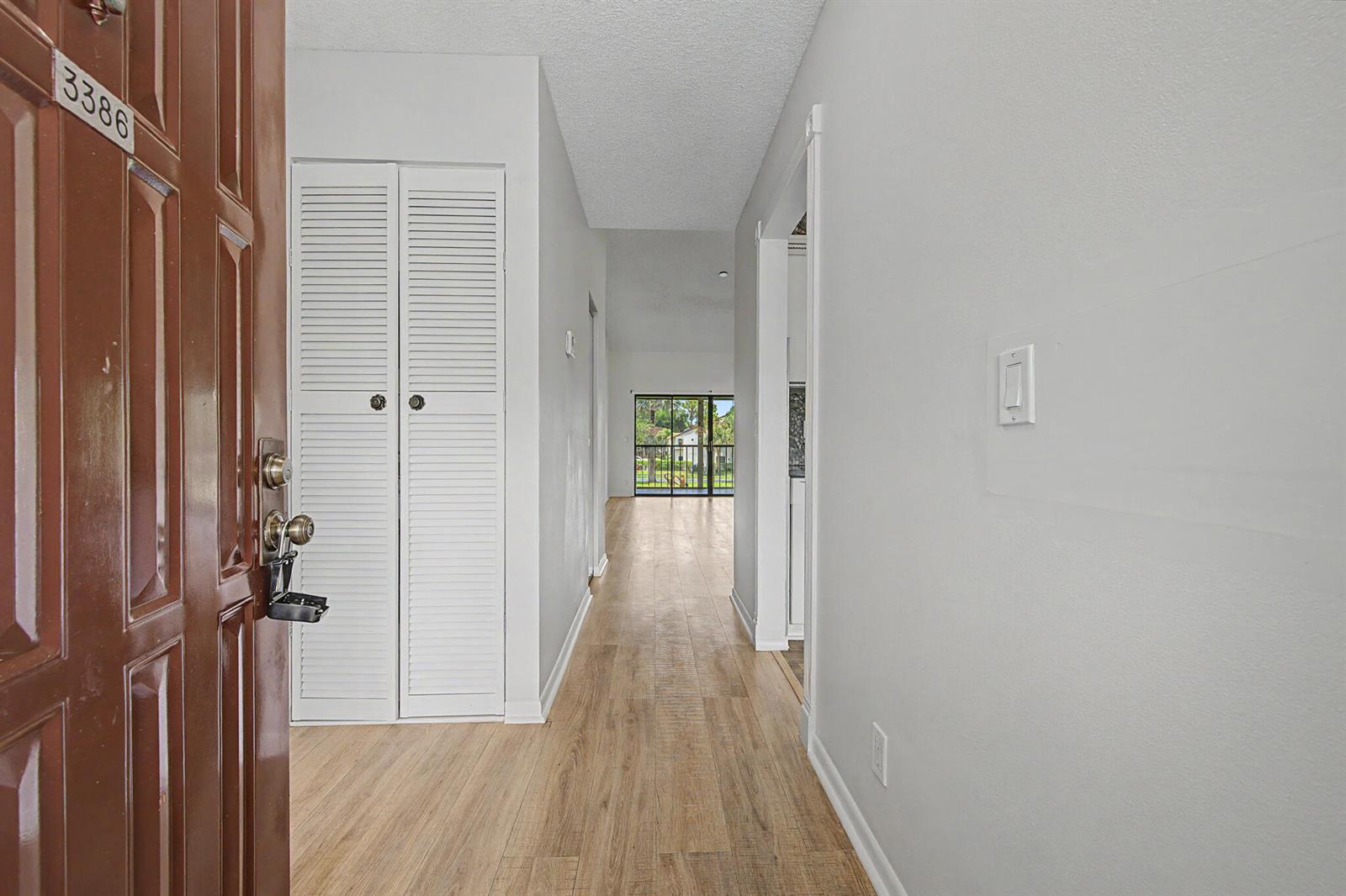 An entryway leads into a hallway with light wood flooring and a white louvered closet — 3386 Lucerne Park Drive, FL 33467, FL