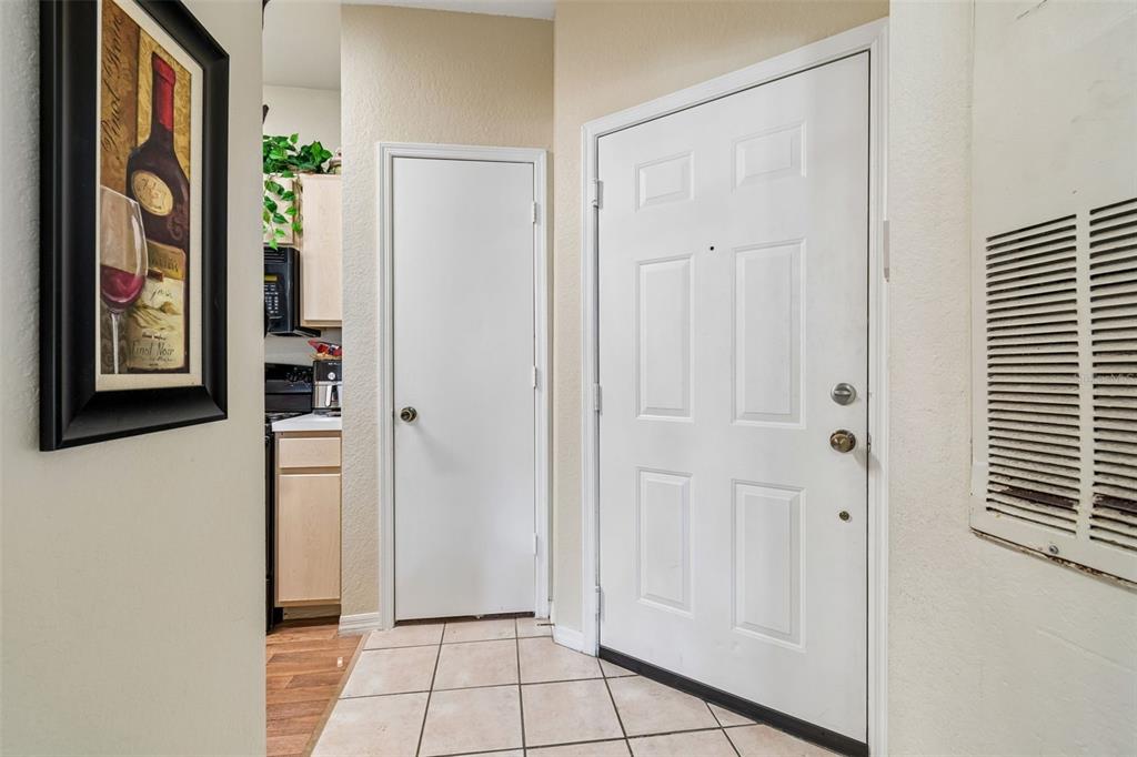 An entryway features a white front door, a closed closet door, and tiled flooring — 8414 LUCUYA WAY UNIT 201, TAMPA, FL