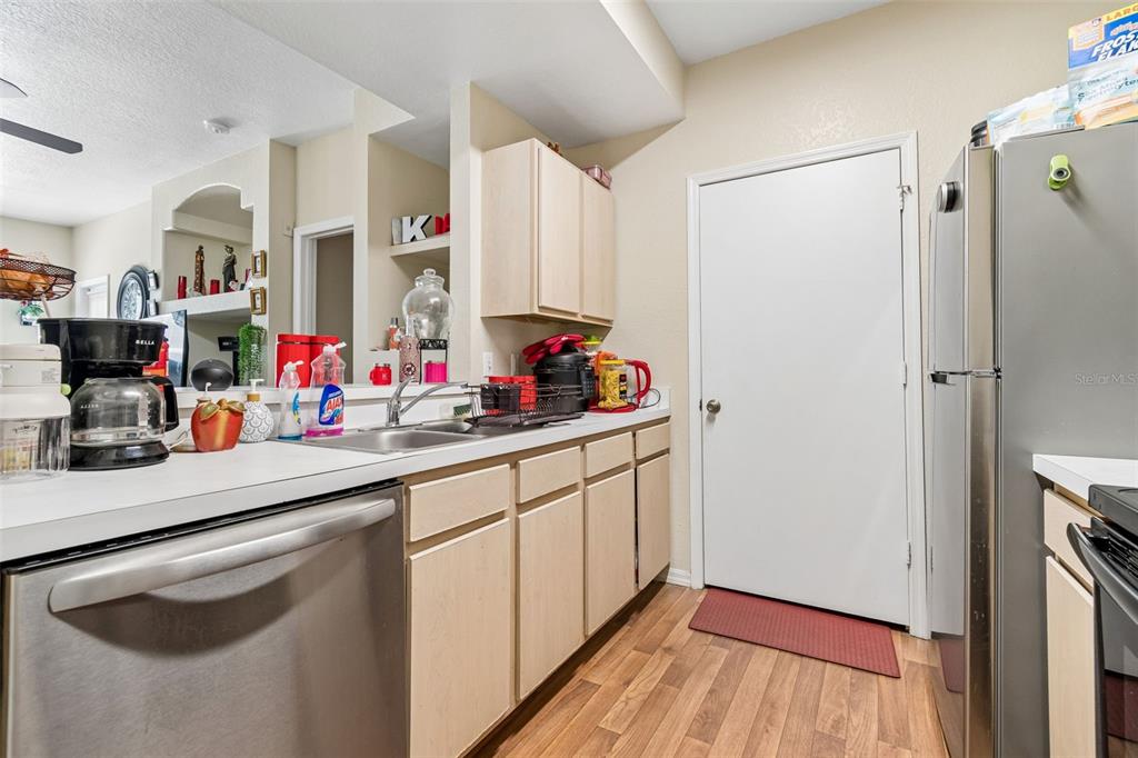 A kitchen features light wood cabinets, stainless steel appliances, and a white door — 8414 LUCUYA WAY UNIT 201, TAMPA, FL