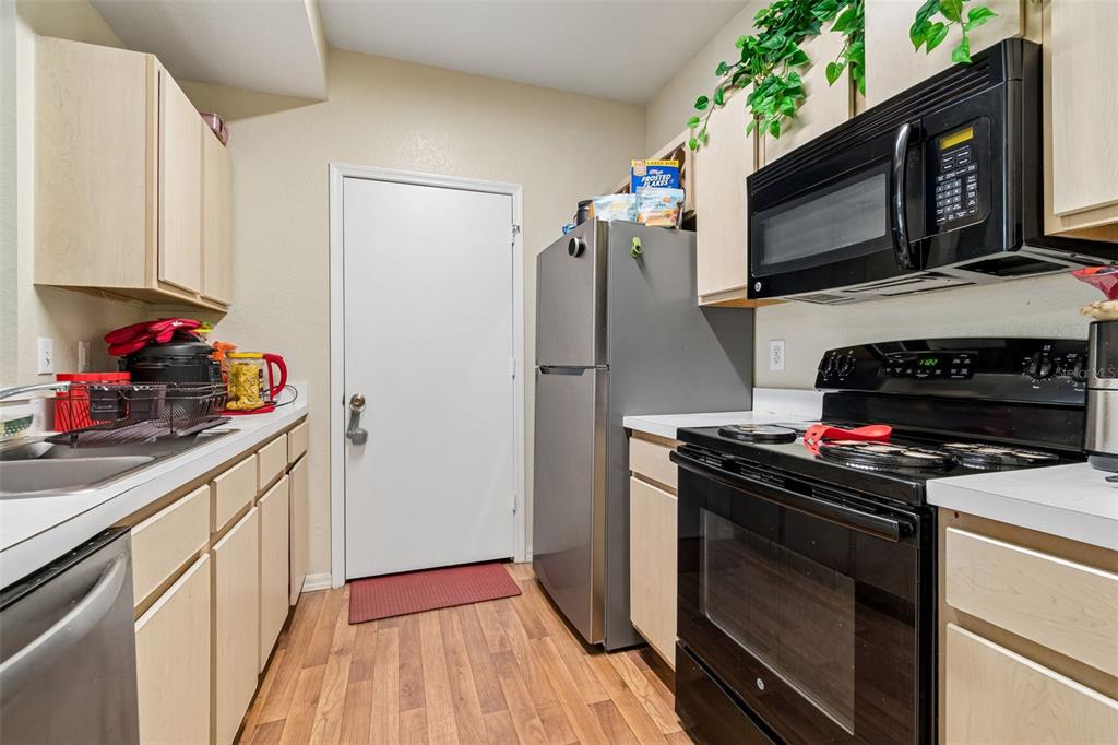 A kitchen features light wood cabinets, stainless steel appliances, and a white door — 8414 LUCUYA WAY UNIT 201, TAMPA, FL