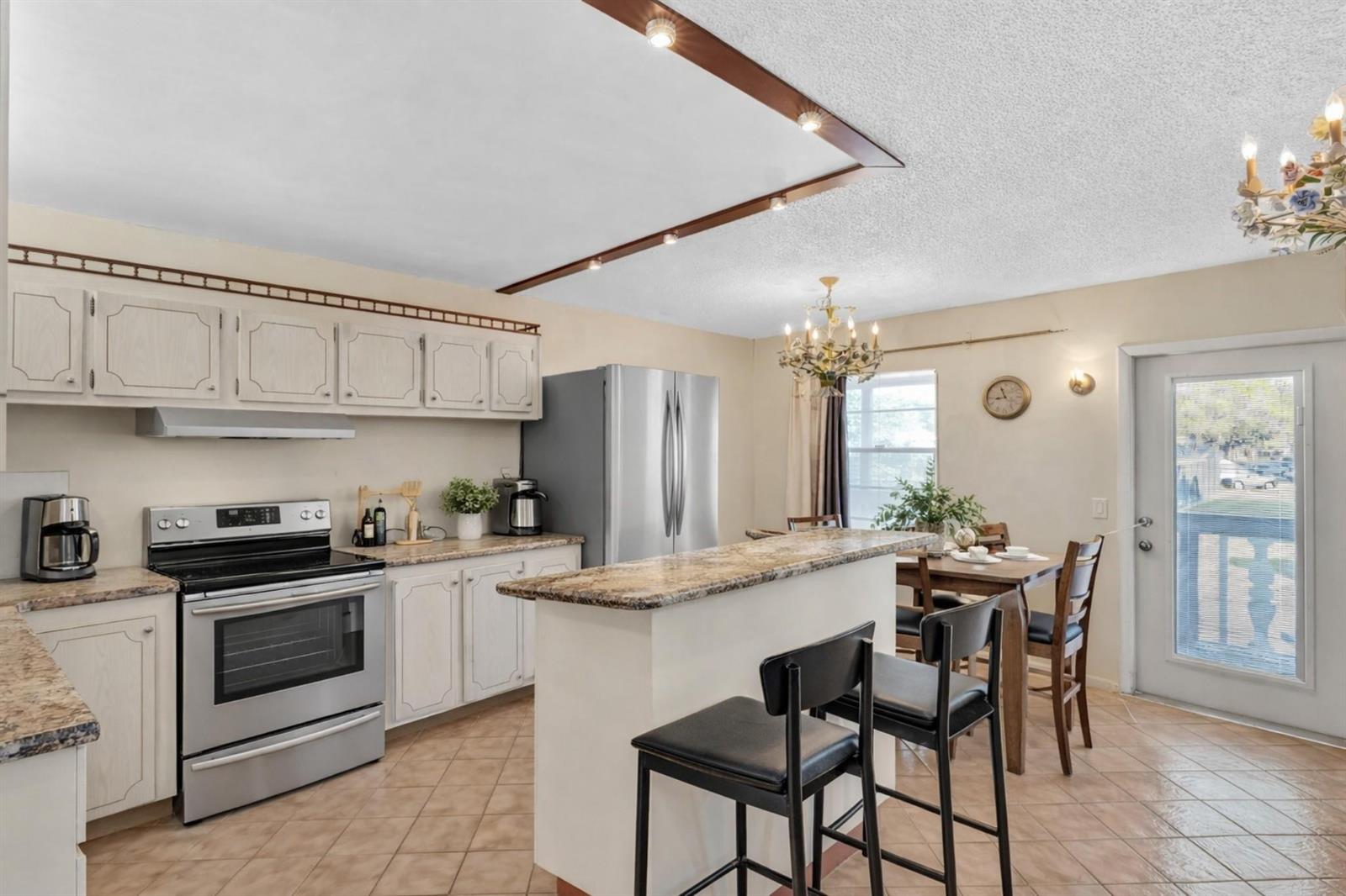 A kitchen with white cabinets, stainless steel appliances, a granite island, and a dining area — 238 Ventnor Q # 238, Deerfield Beach FL 33442, DEERFIELD BEACH, FL
