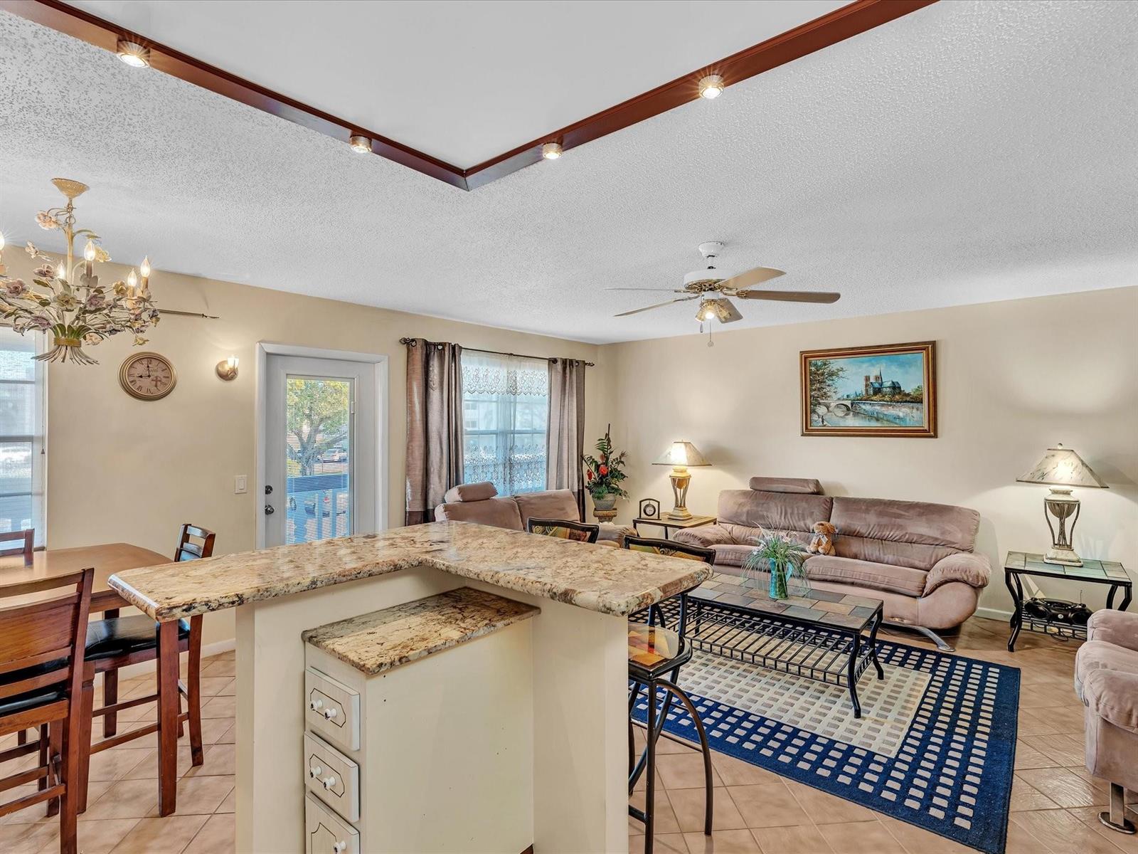 An open-concept living and dining area features a granite-topped kitchen island and tile flooring — 238 Ventnor Q # 238, Deerfield Beach FL 33442, DEERFIELD BEACH, FL