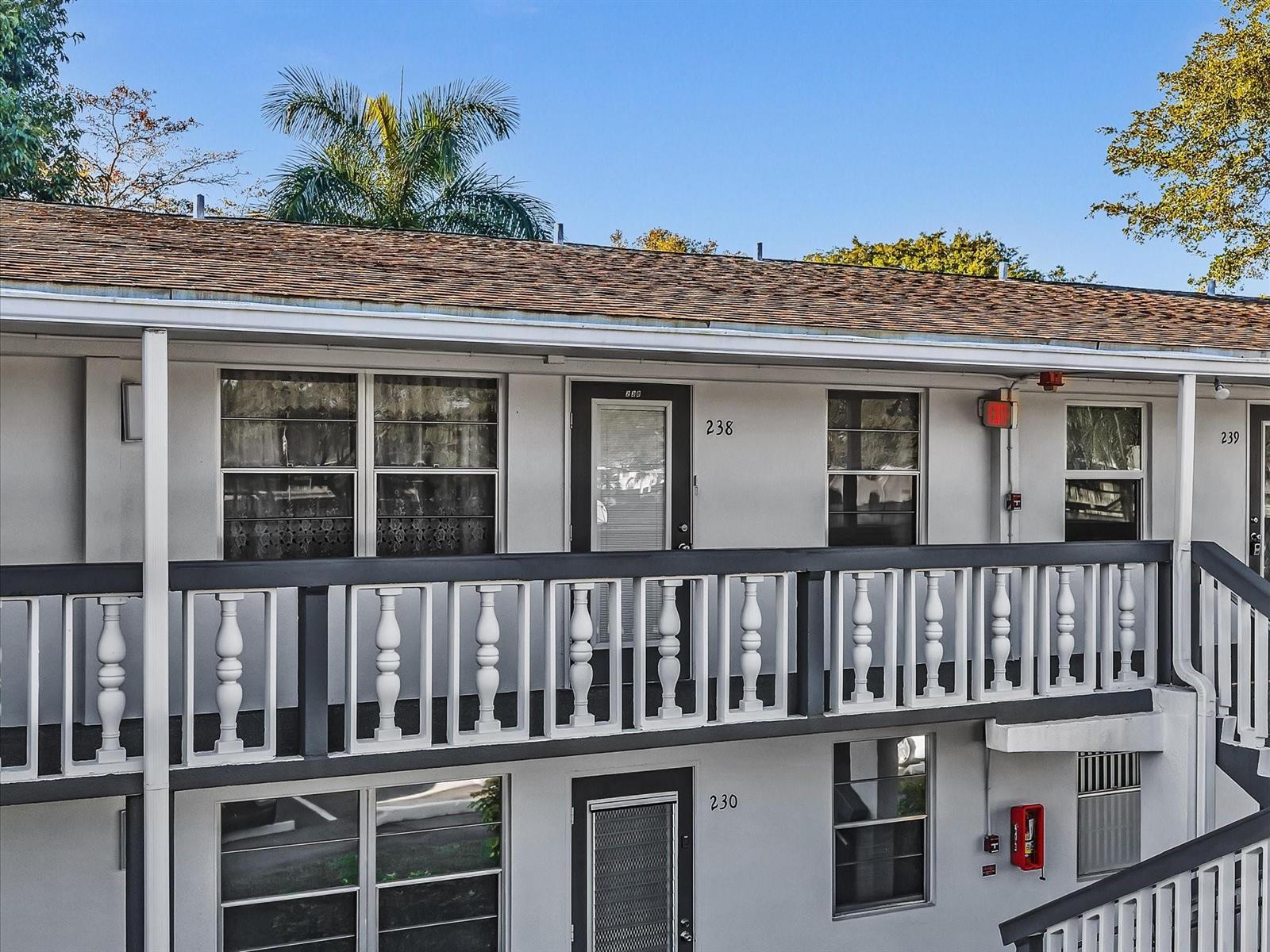 An exterior view of a two-story apartment building with white railings and numbered doors — 238 Ventnor Q # 238, Deerfield Beach FL 33442, DEERFIELD BEACH, FL