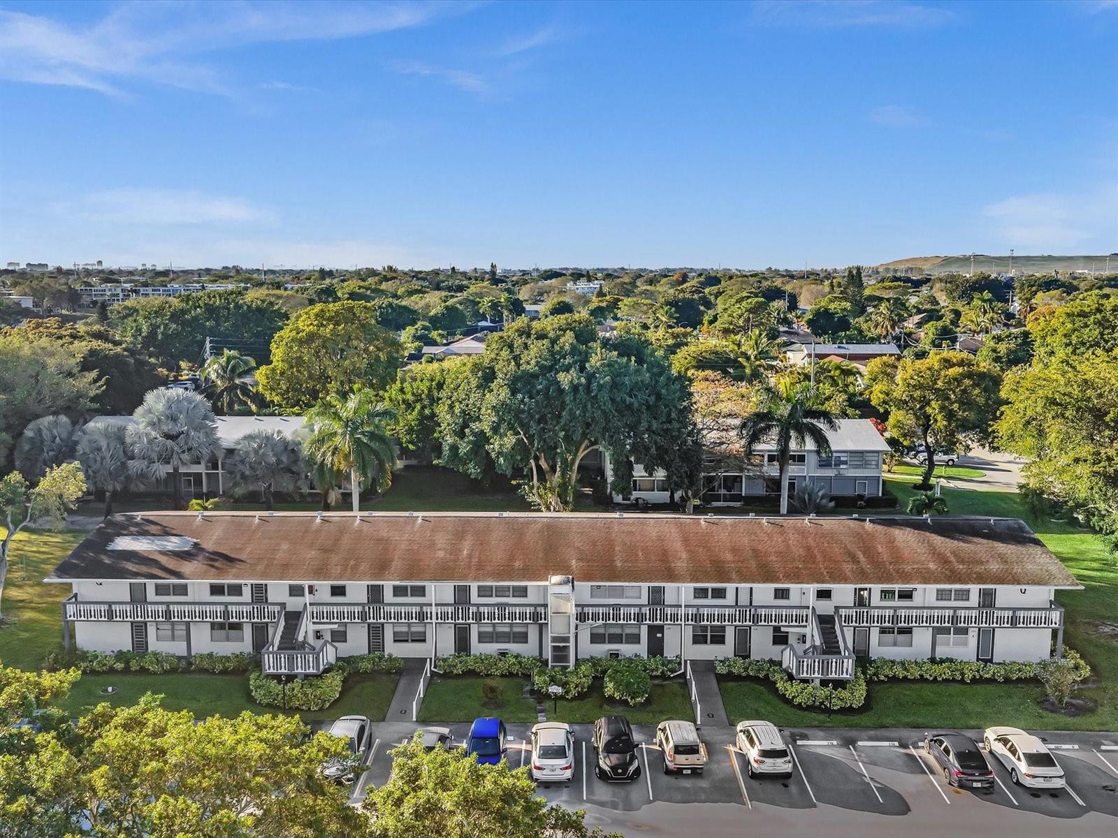 An aerial view shows a long, two-story apartment building with a parking lot in front — 238 Ventnor Q # 238, Deerfield Beach FL 33442, DEERFIELD BEACH, FL