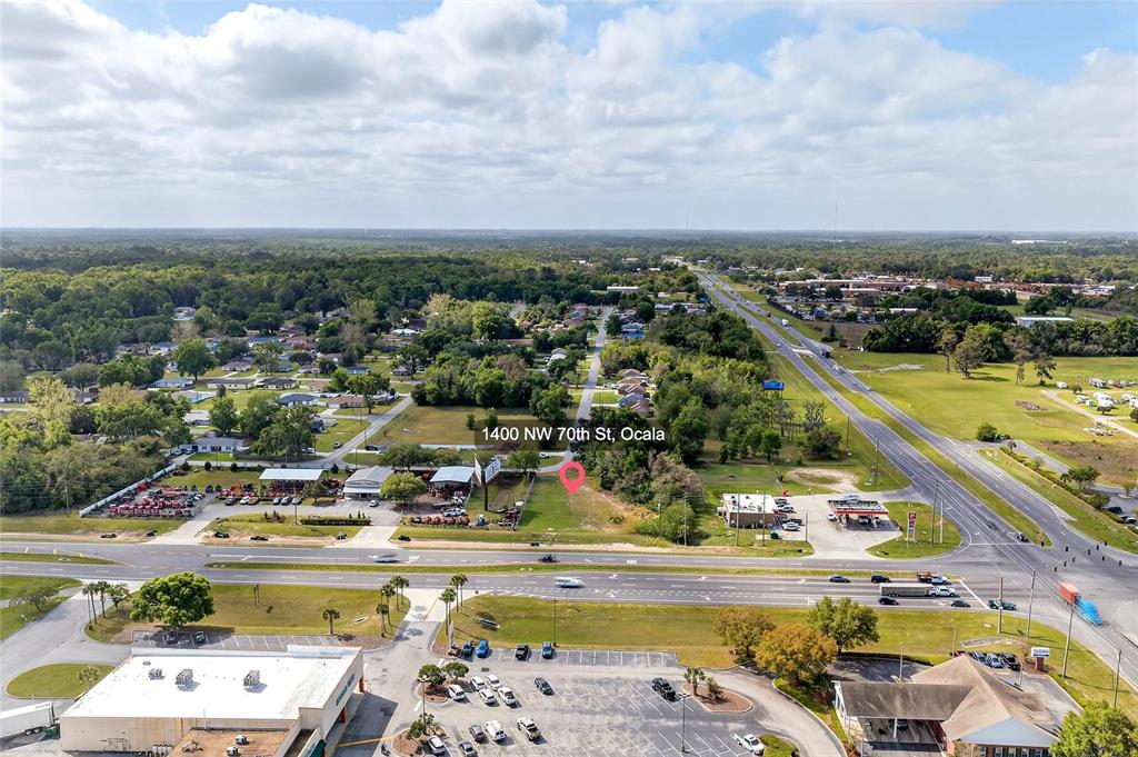 An aerial view shows a vacant lot situated between commercial buildings and a highway — HWY 326 / NW 70TH, OCALA, FL
