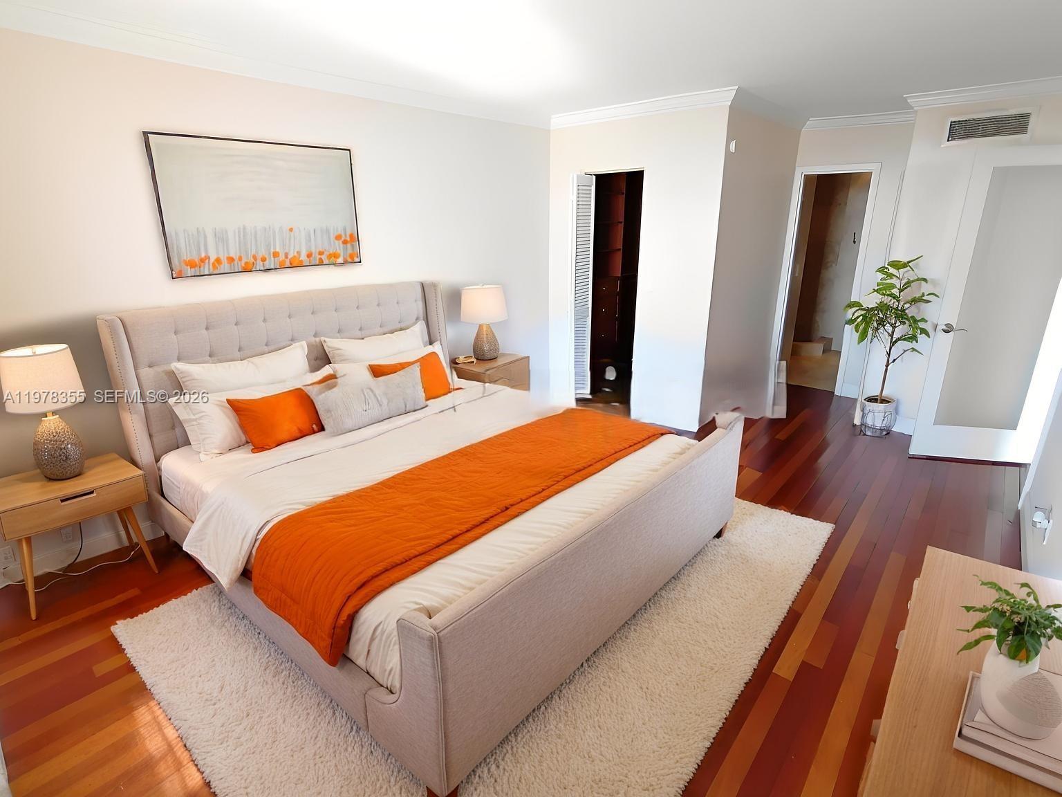 A bedroom features a tufted bed with orange accents, hardwood floors, and a white rug — 2020 NE 135th St # 506, North Miami FL 33181, NORTH MIAMI, FL