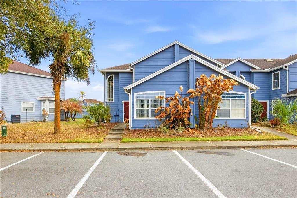 A blue two-story townhouse with a parking lot in the foreground and palm trees — 135 ORCHID DRIVE, DAVENPORT, FL