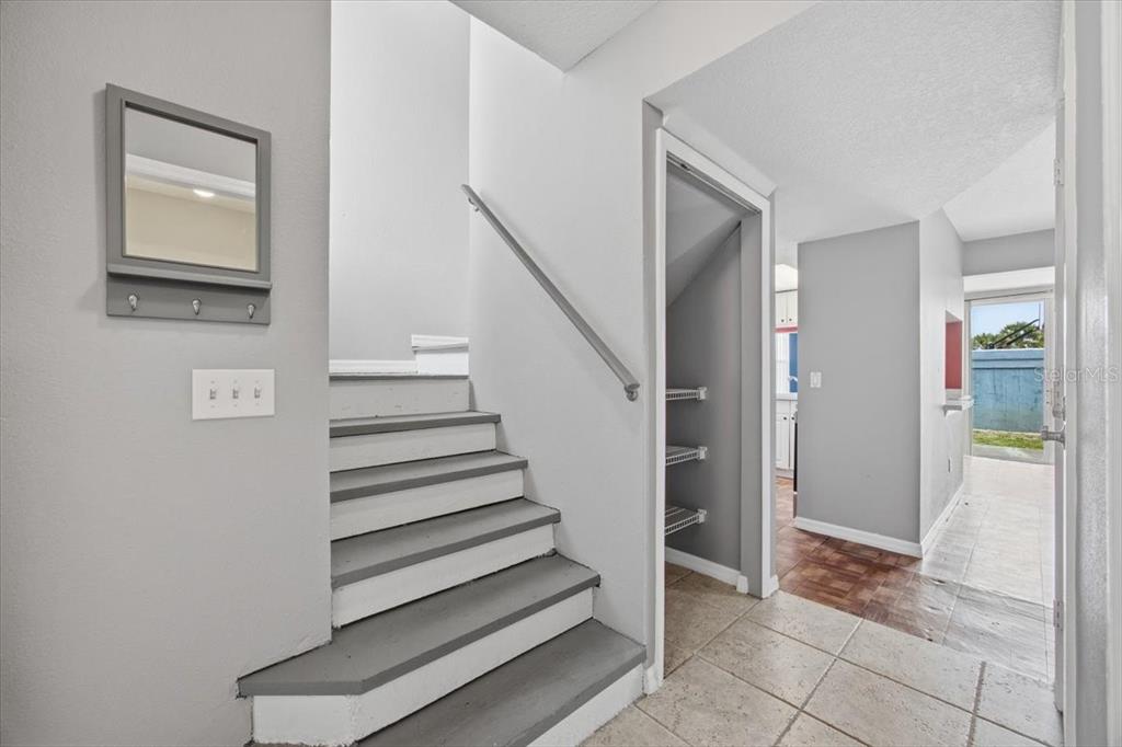A staircase with grey and white steps leads upward next to a small storage closet — 135 ORCHID DRIVE, DAVENPORT, FL