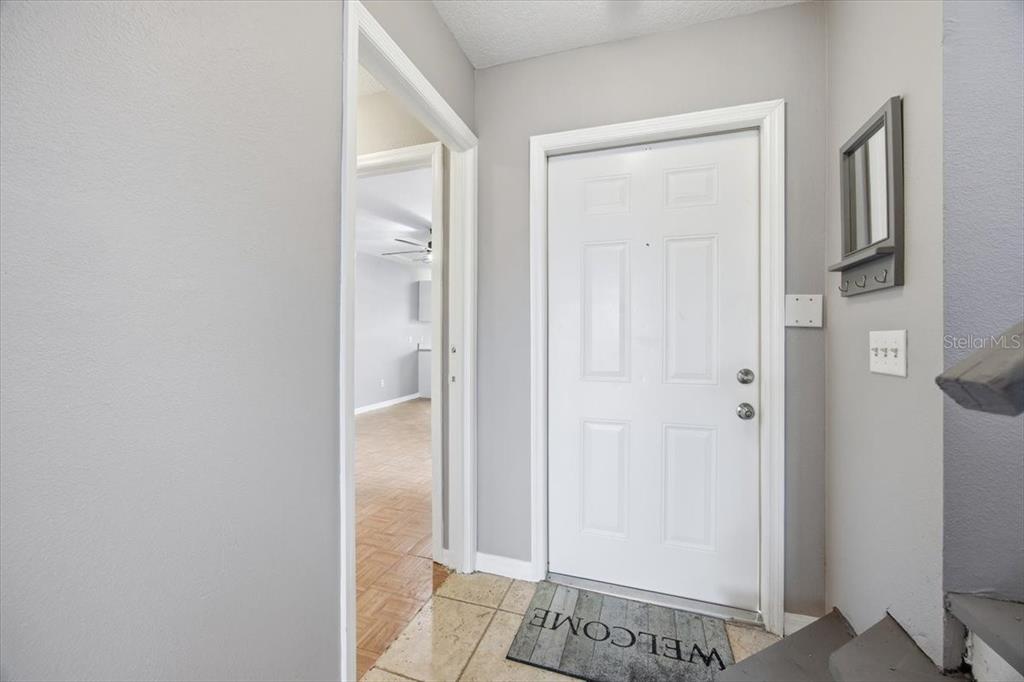 An entryway features a white front door, a welcome mat, and a doorway to another room — 135 ORCHID DRIVE, DAVENPORT, FL