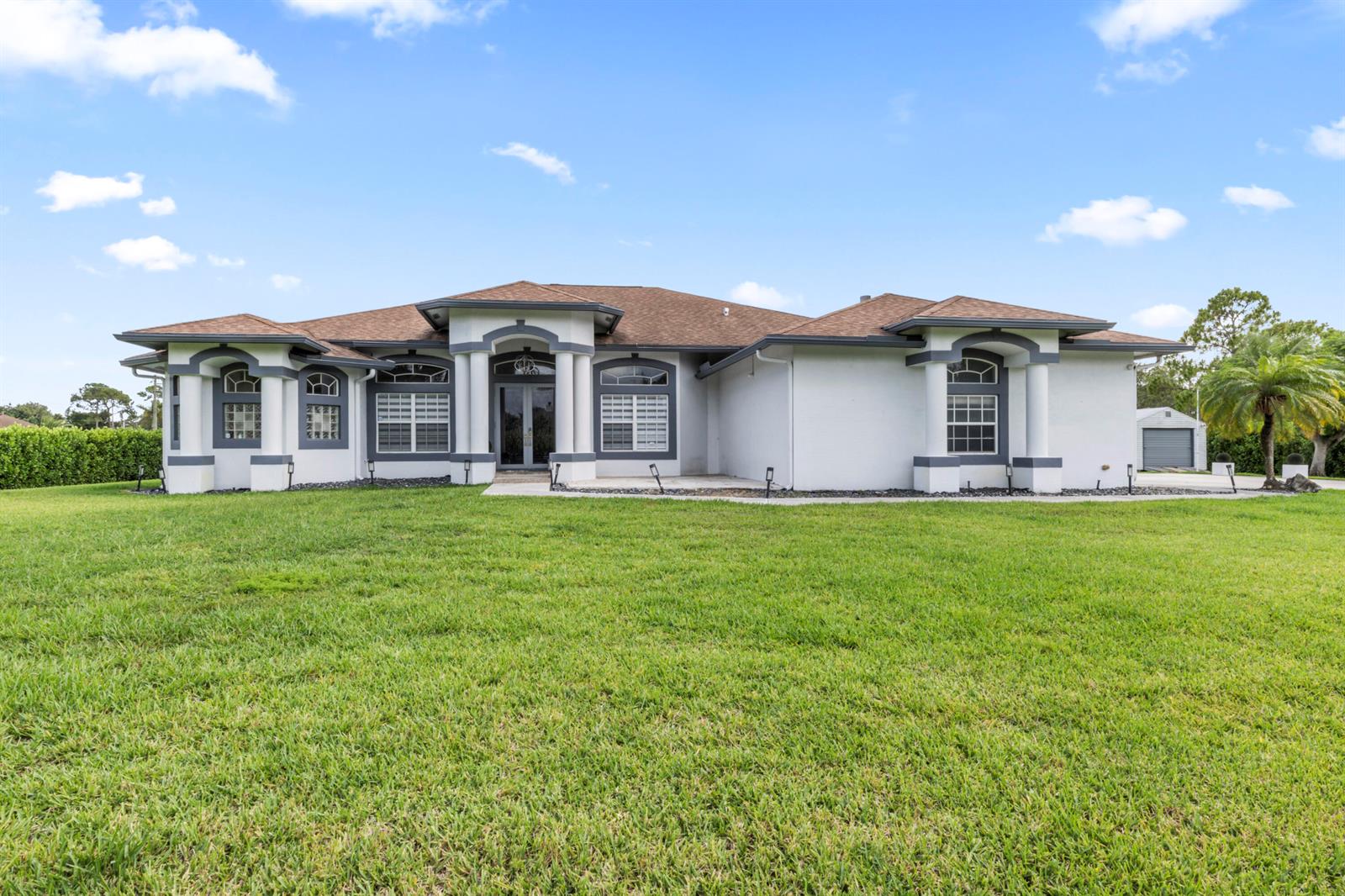 A single-story house with a white stucco exterior, gray trim, and a brown shingled roof — 15062 N 73rd St Street N, FL 33470, FL