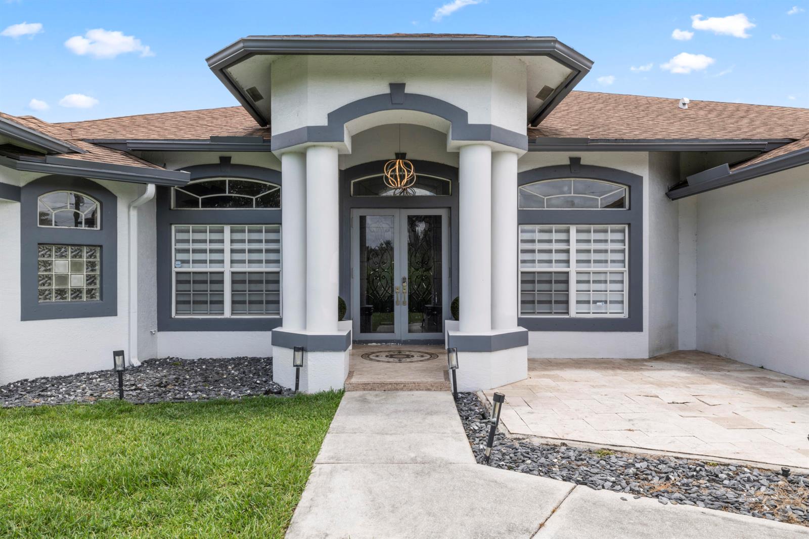 The exterior of a house features a covered entryway with columns and a double door — 15062 N 73rd St Street N, FL 33470, FL