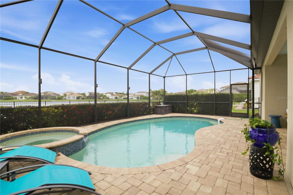 A screened-in pool and spa area with paver decking overlooking a lake and neighborhood — 13422 SAW PALM CREEK TRAIL, LAKEWOOD RANCH, FL