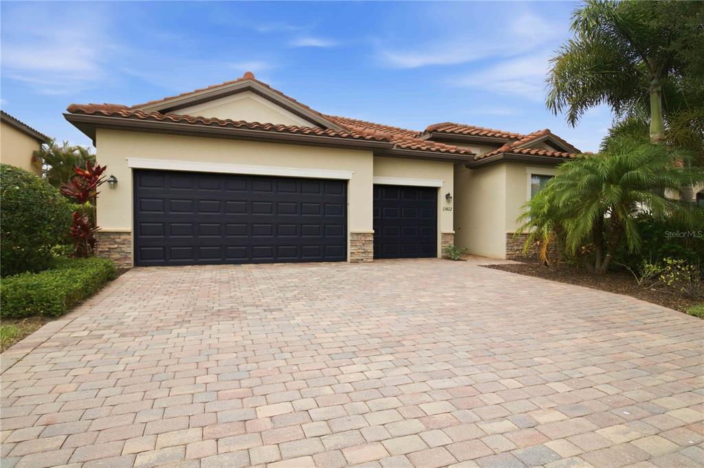 A single-story house with a tan stucco exterior, tile roof, and a paved driveway — 13422 SAW PALM CREEK TRAIL, LAKEWOOD RANCH, FL