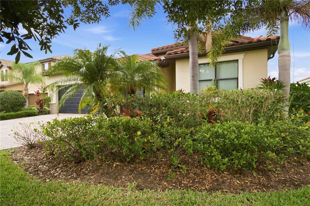 A tan stucco house with a tile roof and a landscaped front yard — 13422 SAW PALM CREEK TRAIL, LAKEWOOD RANCH, FL