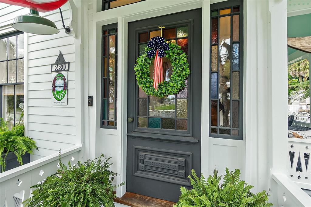 A dark gray front door with a patriotic wreath is flanked by sidelights and ferns — 220 S 4TH STREET, PALATKA, FL