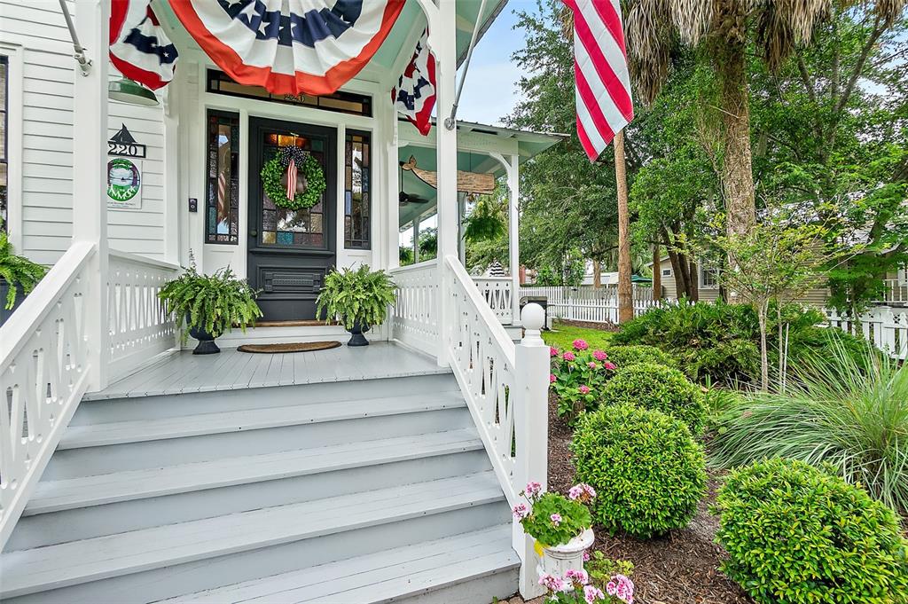 A front porch with grey steps, white railings, and patriotic bunting leads to a dark door — 220 S 4TH STREET, PALATKA, FL