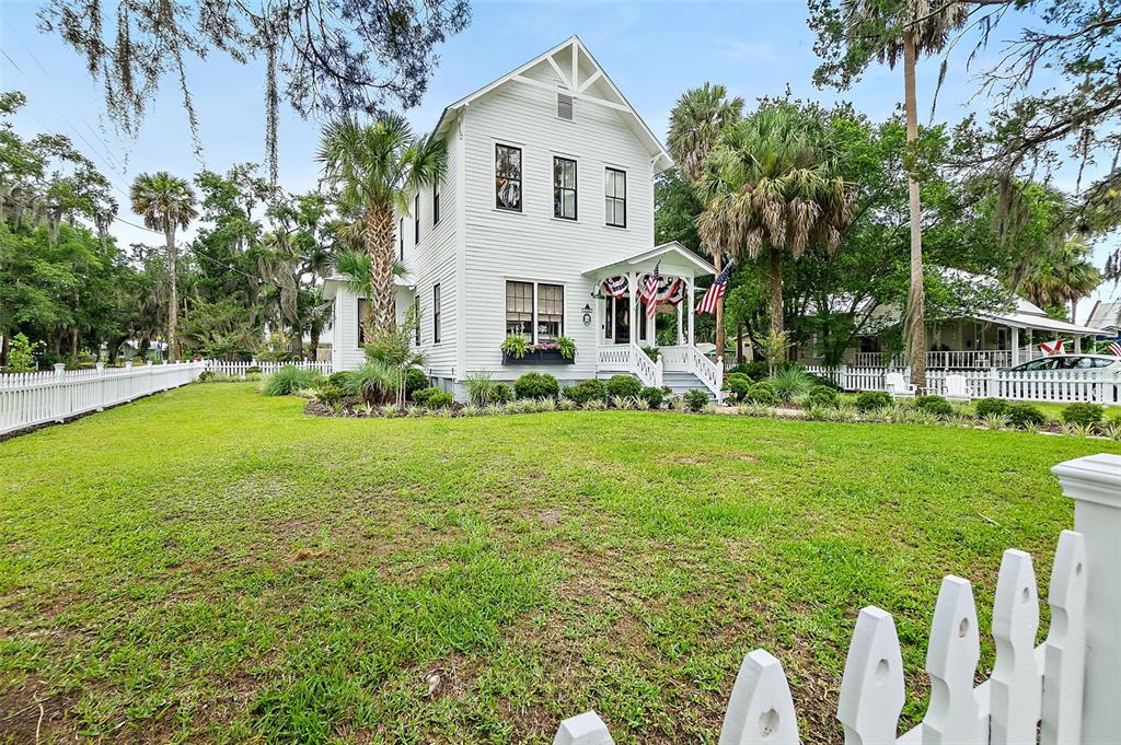 A white two-story house with a front porch stands behind a white picket fence — 220 S 4TH STREET, PALATKA, FL