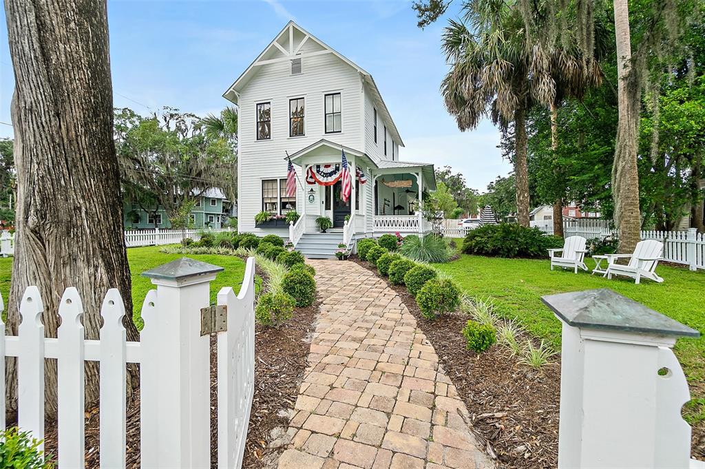 A white two-story house with a brick walkway and a picket fence in the yard — 220 S 4TH STREET, PALATKA, FL