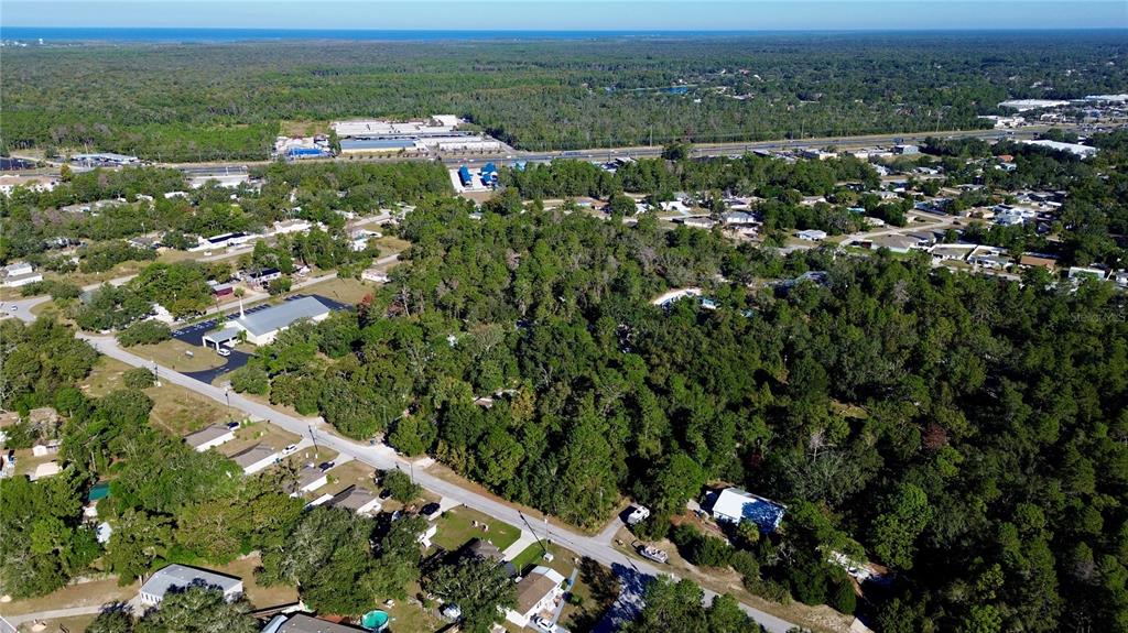 An aerial view shows a wooded residential neighborhood with a church and nearby highway — 7049 CENTERWOOD AVENUE, SPRING HILL, FL