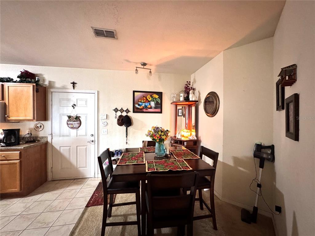 A dining area features a dark wood table with four chairs and a corner display cabinet — 5550 E MICHIGAN STREET UNIT 2112, ORLANDO, FL