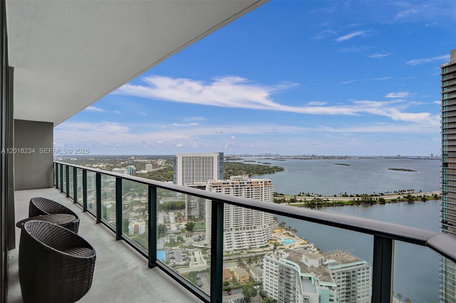 A balcony with two chairs overlooks a bay, city buildings, and a bridge — 501 NE 31st St # 3706, Miami FL 33137, MIAMI, FL