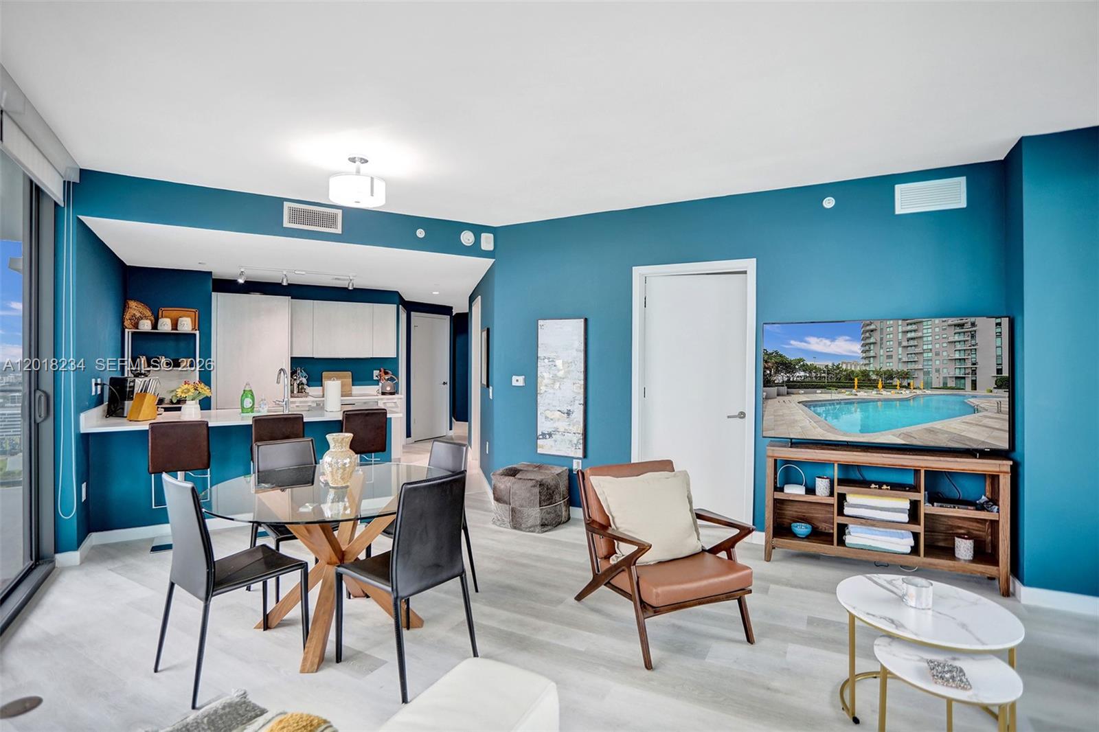 A living and dining area features blue walls, a glass table, and a television console — 501 NE 31st St # 3706, Miami FL 33137, MIAMI, FL