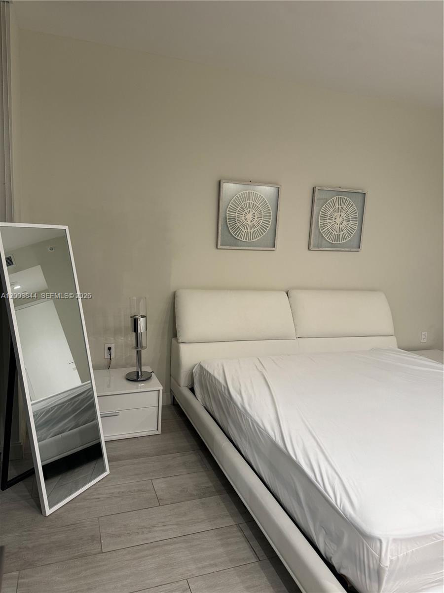 A bedroom features a white platform bed, a floor mirror, and two wall-mounted circular artworks — 55 SW 9th St # 1204, Miami FL 33130, MIAMI, FL