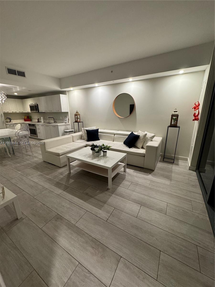 A modern living room features a white sectional sofa, a coffee table, and light wood-look flooring — 55 SW 9th St # 1204, Miami FL 33130, MIAMI, FL